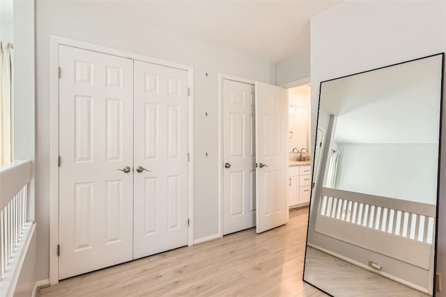 bedroom with a sink, baseboards, and light wood-style flooring