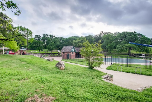 view of home's community with a playground, a yard, and fence