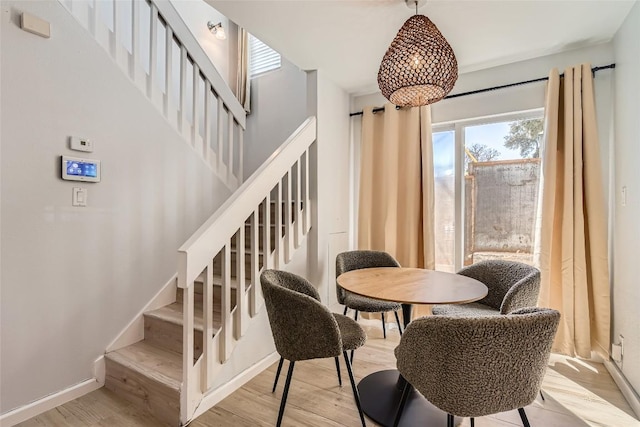 dining area featuring stairs, baseboards, and wood finished floors