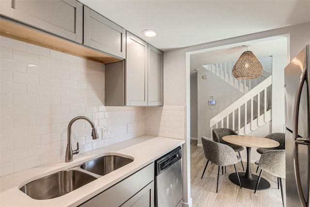 kitchen with a sink, stainless steel appliances, light wood-type flooring, and light countertops