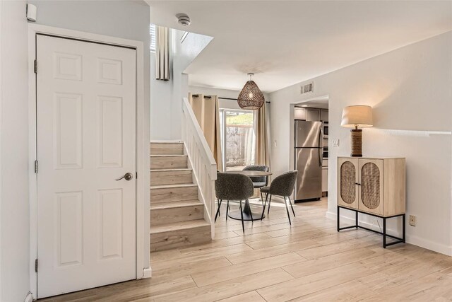 stairway with visible vents, baseboards, and wood finished floors