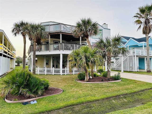 rear view of property with concrete driveway, a yard, and fence