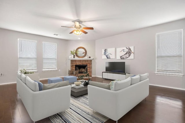 living area with visible vents, baseboards, dark wood-type flooring, and a brick fireplace