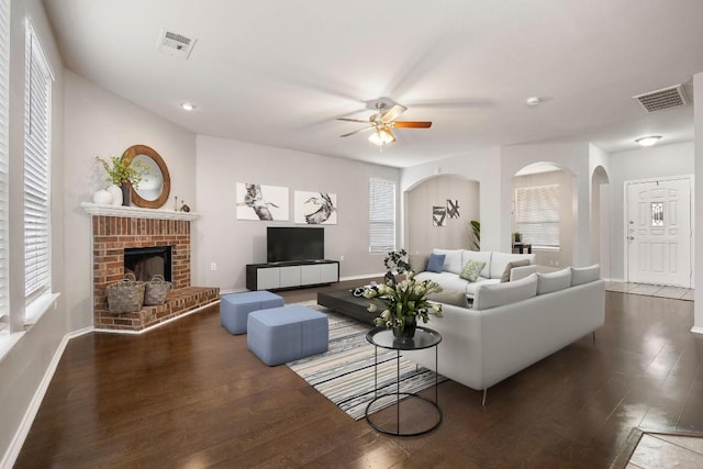 living room featuring visible vents, baseboards, wood finished floors, and a fireplace