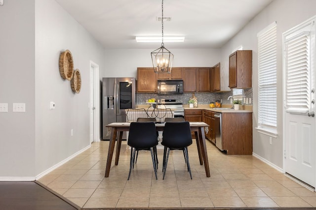 kitchen featuring visible vents, pendant lighting, a sink, tasteful backsplash, and appliances with stainless steel finishes