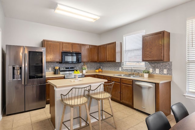 kitchen with a sink, tasteful backsplash, a center island, stainless steel appliances, and light countertops