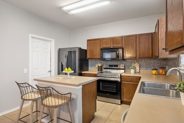 kitchen featuring a sink, tasteful backsplash, appliances with stainless steel finishes, and light tile patterned floors