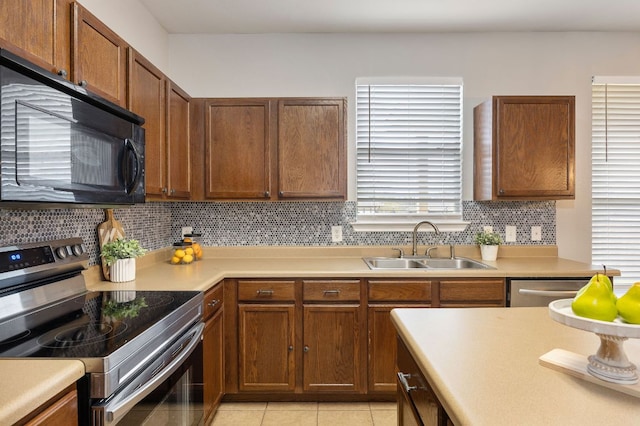 kitchen featuring a sink, appliances with stainless steel finishes, light tile patterned flooring, light countertops, and decorative backsplash