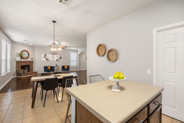 kitchen with light tile patterned floors, visible vents, arched walkways, a brick fireplace, and open floor plan