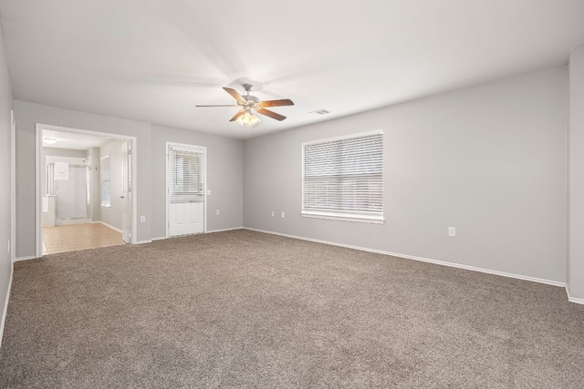 carpeted empty room featuring visible vents, baseboards, and ceiling fan