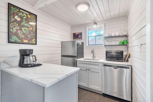 kitchen with a toaster, wood ceiling, light stone counters, stainless steel appliances, and a sink