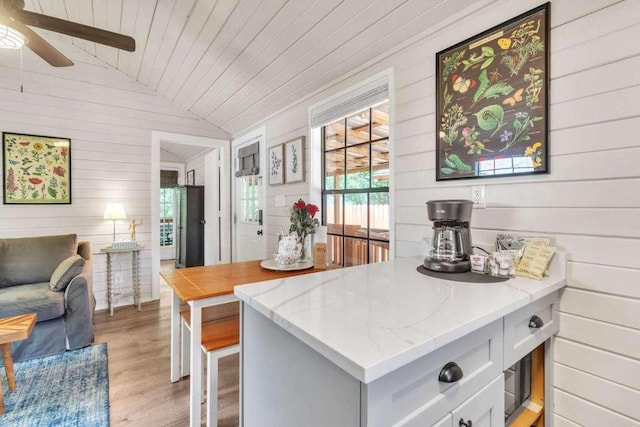 kitchen featuring light wood-type flooring, white cabinetry, lofted ceiling, wood ceiling, and light stone countertops