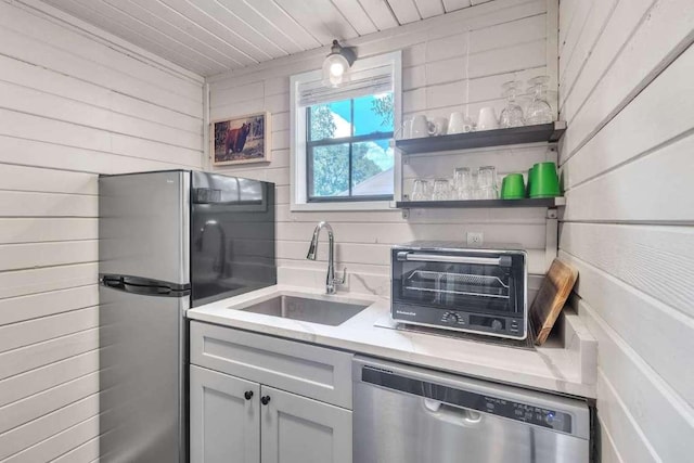 kitchen featuring a toaster, a sink, stainless steel appliances, light countertops, and tasteful backsplash