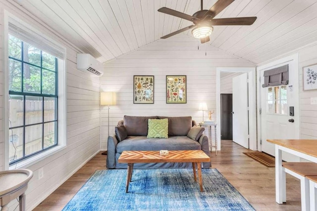 living room with vaulted ceiling, a healthy amount of sunlight, wood finished floors, and a wall mounted AC