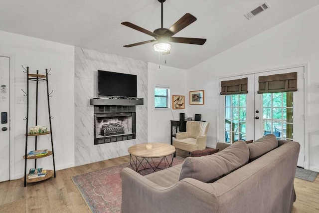 living room with lofted ceiling, wood finished floors, visible vents, and a high end fireplace