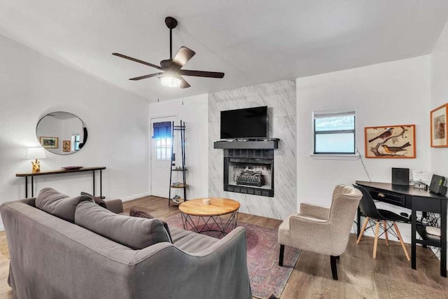 living area with a ceiling fan, wood finished floors, a fireplace, and baseboards