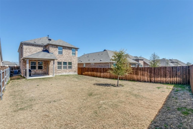 back of house featuring a lawn, brick siding, and a fenced backyard