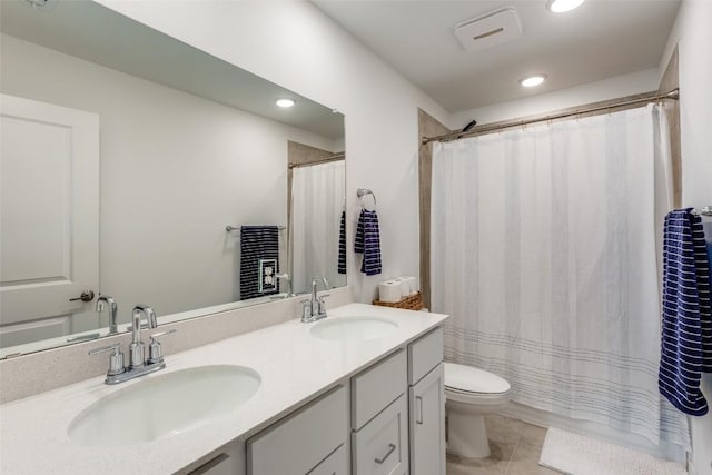 full bathroom featuring double vanity, toilet, tile patterned floors, and a sink