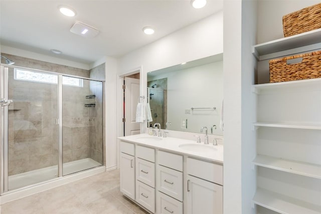 bathroom with a shower stall, recessed lighting, double vanity, and a sink