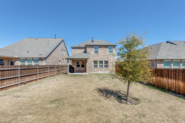 rear view of house featuring a yard, brick siding, and a fenced backyard