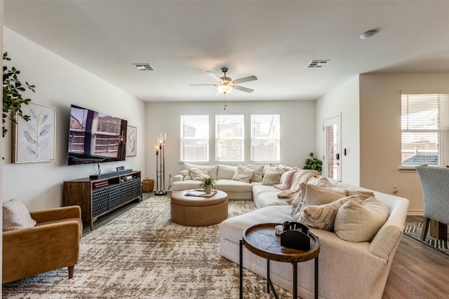 living area with a wealth of natural light, visible vents, and wood finished floors