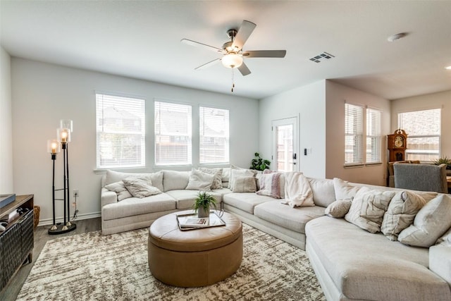 living room with wood finished floors, a ceiling fan, visible vents, and baseboards