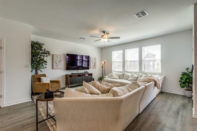 living room featuring visible vents, baseboards, a ceiling fan, and wood finished floors