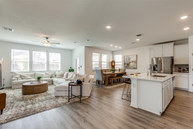 kitchen with a wealth of natural light, visible vents, a sink, open floor plan, and stainless steel fridge with ice dispenser