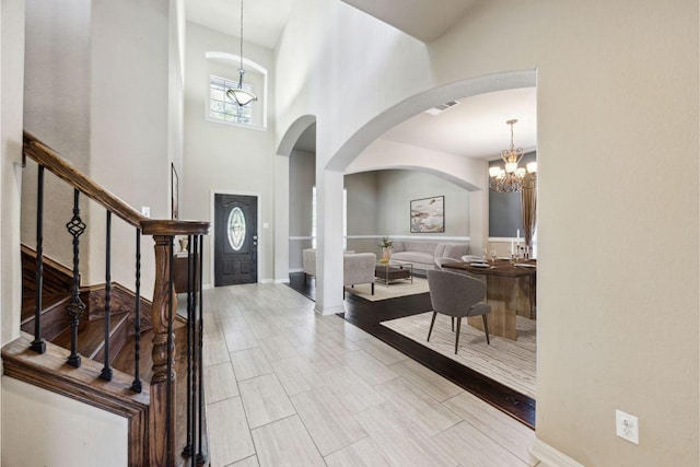 entrance foyer featuring stairway, visible vents, baseboards, and a towering ceiling