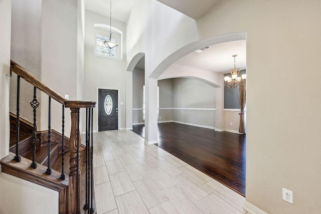 entryway featuring baseboards, arched walkways, an inviting chandelier, and a high ceiling