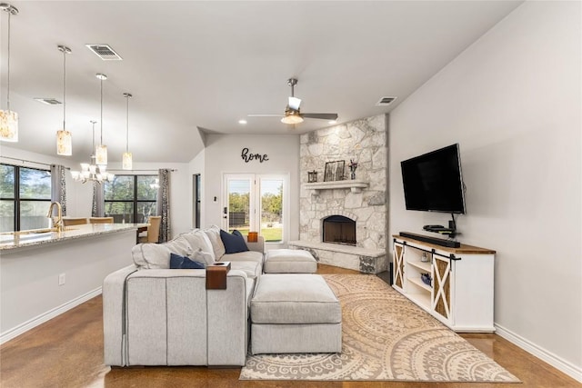 living room with a fireplace, ceiling fan with notable chandelier, visible vents, and baseboards