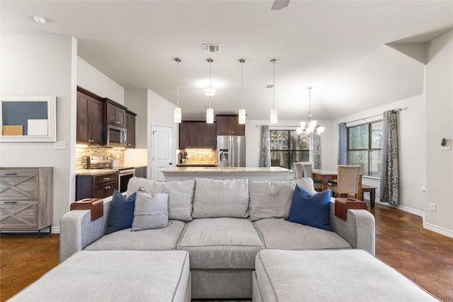 living room featuring visible vents, baseboards, concrete floors, and a chandelier