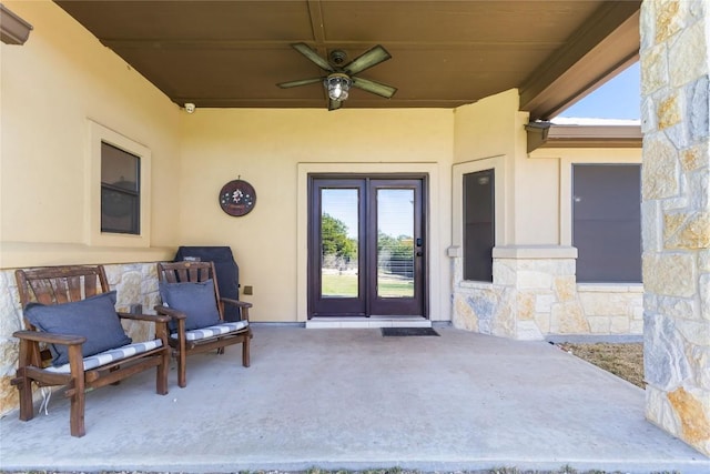 entrance to property featuring a ceiling fan, stone siding, and stucco siding