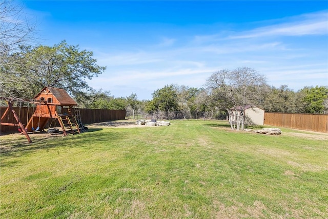 view of yard with an outbuilding, a fenced backyard, a storage shed, and a playground