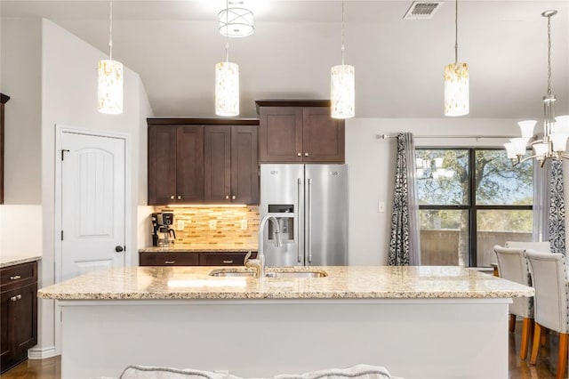 kitchen featuring visible vents, lofted ceiling, stainless steel fridge with ice dispenser, a sink, and dark brown cabinets