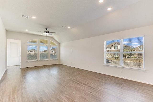 unfurnished living room with a wealth of natural light, visible vents, wood finished floors, and a ceiling fan