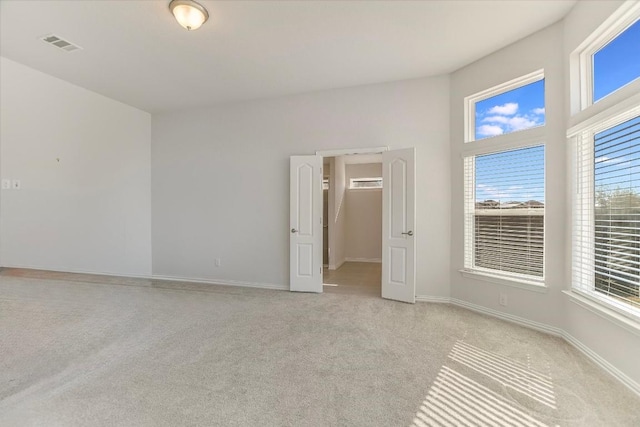 spare room with baseboards, visible vents, and light colored carpet