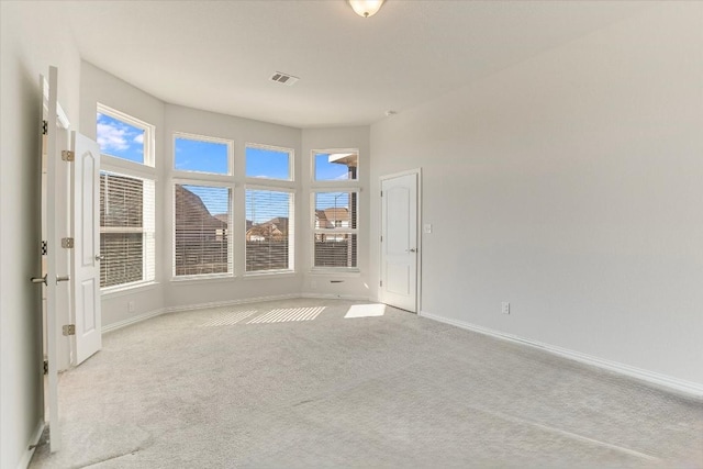carpeted empty room with baseboards, a wealth of natural light, and visible vents
