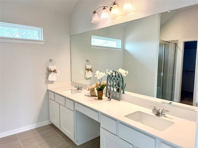 bathroom featuring a sink, double vanity, a stall shower, and baseboards