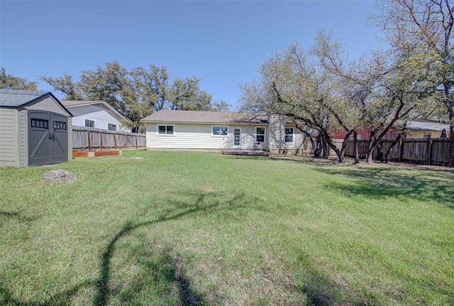 view of yard featuring a fenced backyard, a storage unit, and an outdoor structure