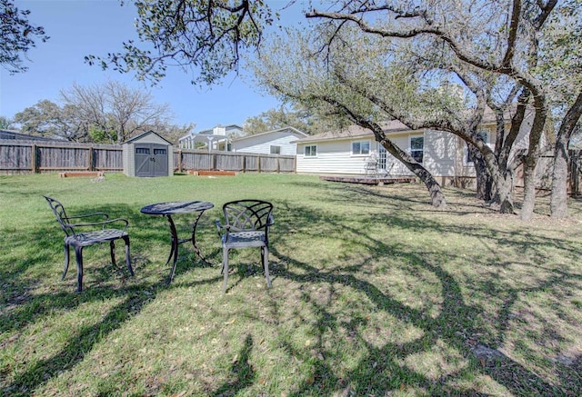 view of yard with an outdoor structure, a fenced backyard, and a shed