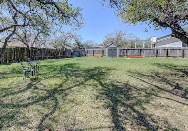 view of yard with an outbuilding, a fenced backyard, and a shed