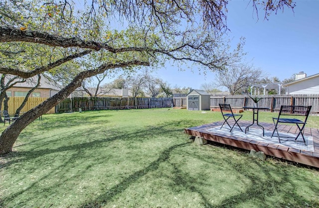 view of yard with a deck, an outbuilding, a storage unit, and a fenced backyard