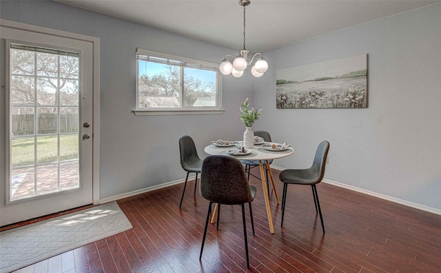 dining area with an inviting chandelier, baseboards, and dark wood-style flooring