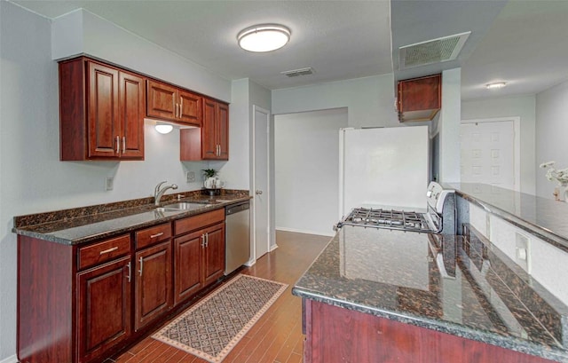 kitchen with visible vents, dishwasher, dark stone countertops, freestanding refrigerator, and dark wood-style floors