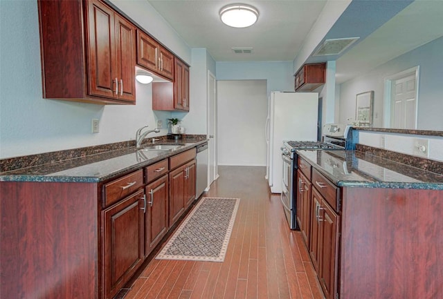 kitchen with visible vents, dark stone counters, a sink, dark wood-type flooring, and appliances with stainless steel finishes