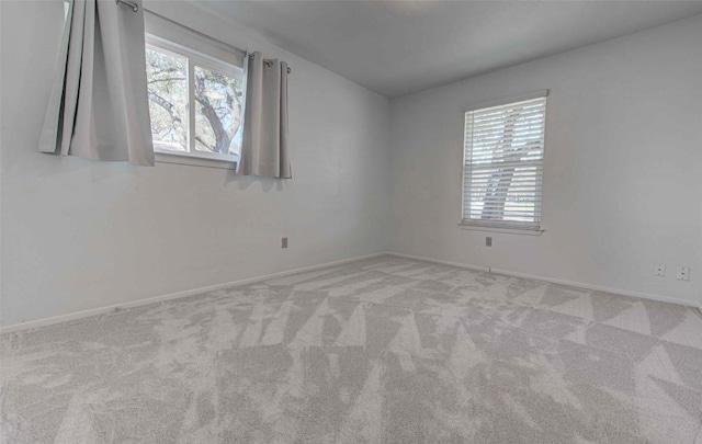 carpeted spare room with plenty of natural light and baseboards