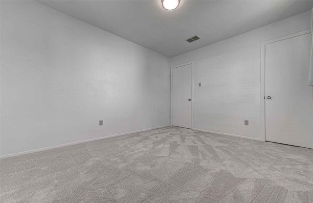 empty room with visible vents, light colored carpet, and baseboards