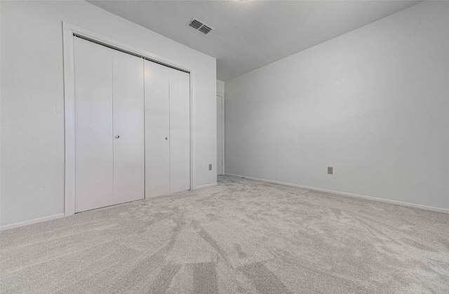 unfurnished bedroom featuring carpet flooring, baseboards, visible vents, and a closet