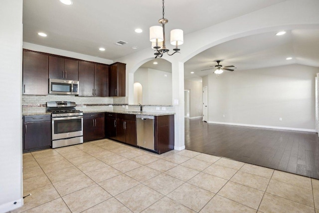 kitchen with visible vents, a sink, stainless steel appliances, arched walkways, and dark brown cabinets